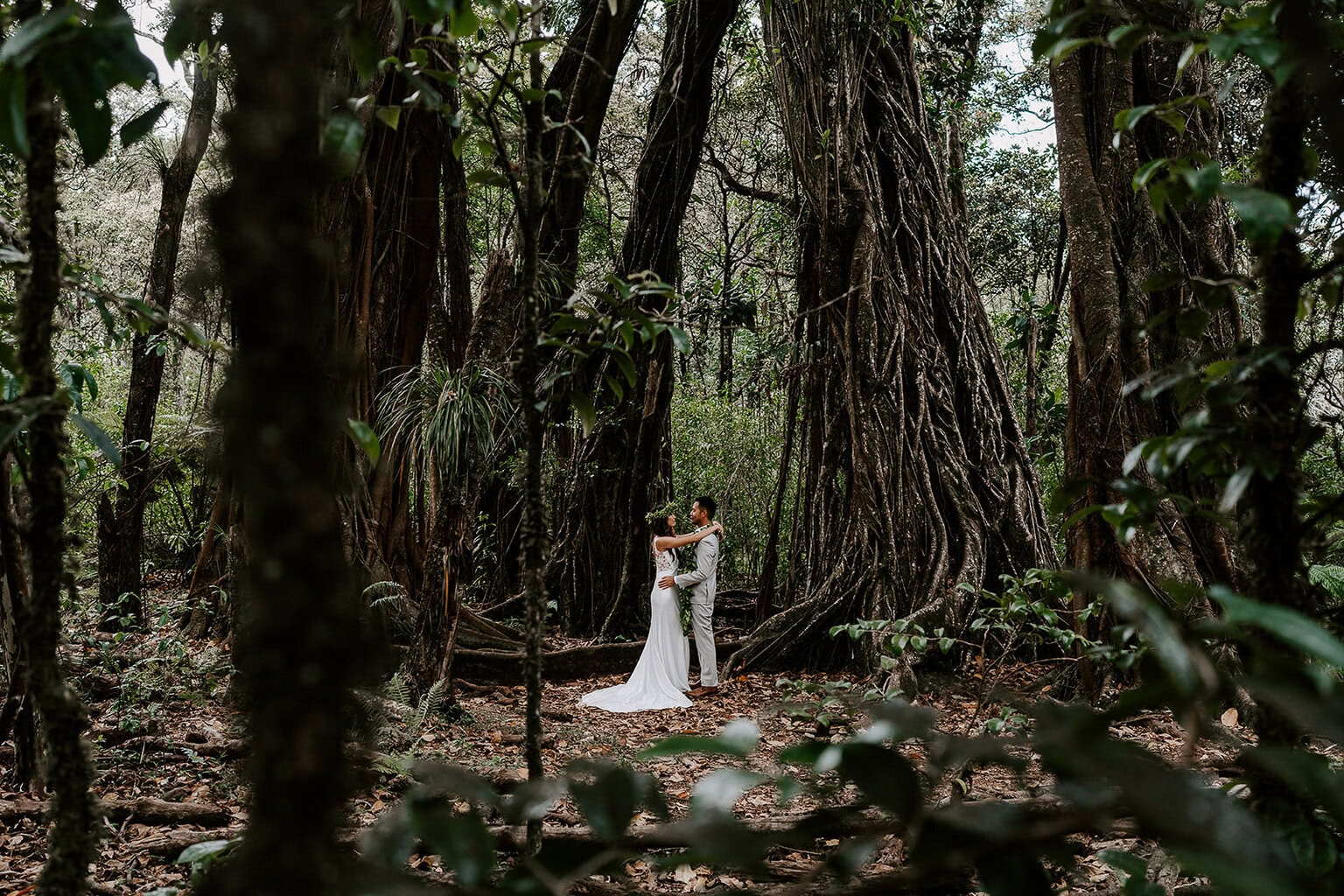 newlyweds embracing each other in a lush jungle.
