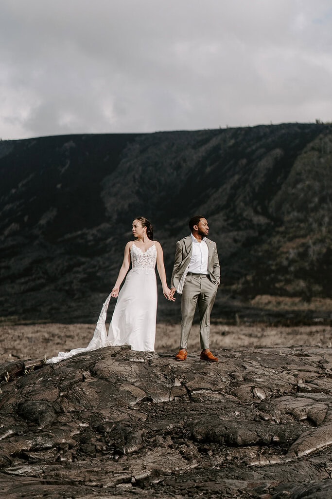 newlyweds holding hands on a lava field during their Big Island elopement.