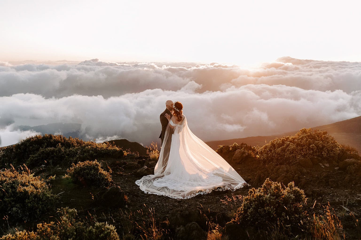 newlyweds kissing above the clouds in Hawaii.