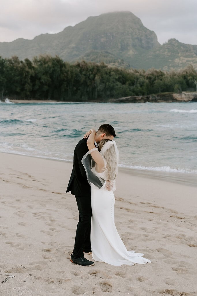 newlyweds kissing on a kauai beach as they elope in Hawaii.