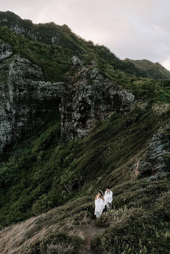Newlyweds walking up a mountain trail during their Oahu elopement.