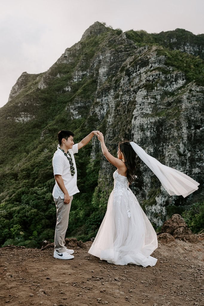 Newlyweds dancing on a cliffside during their Oahu elopement.