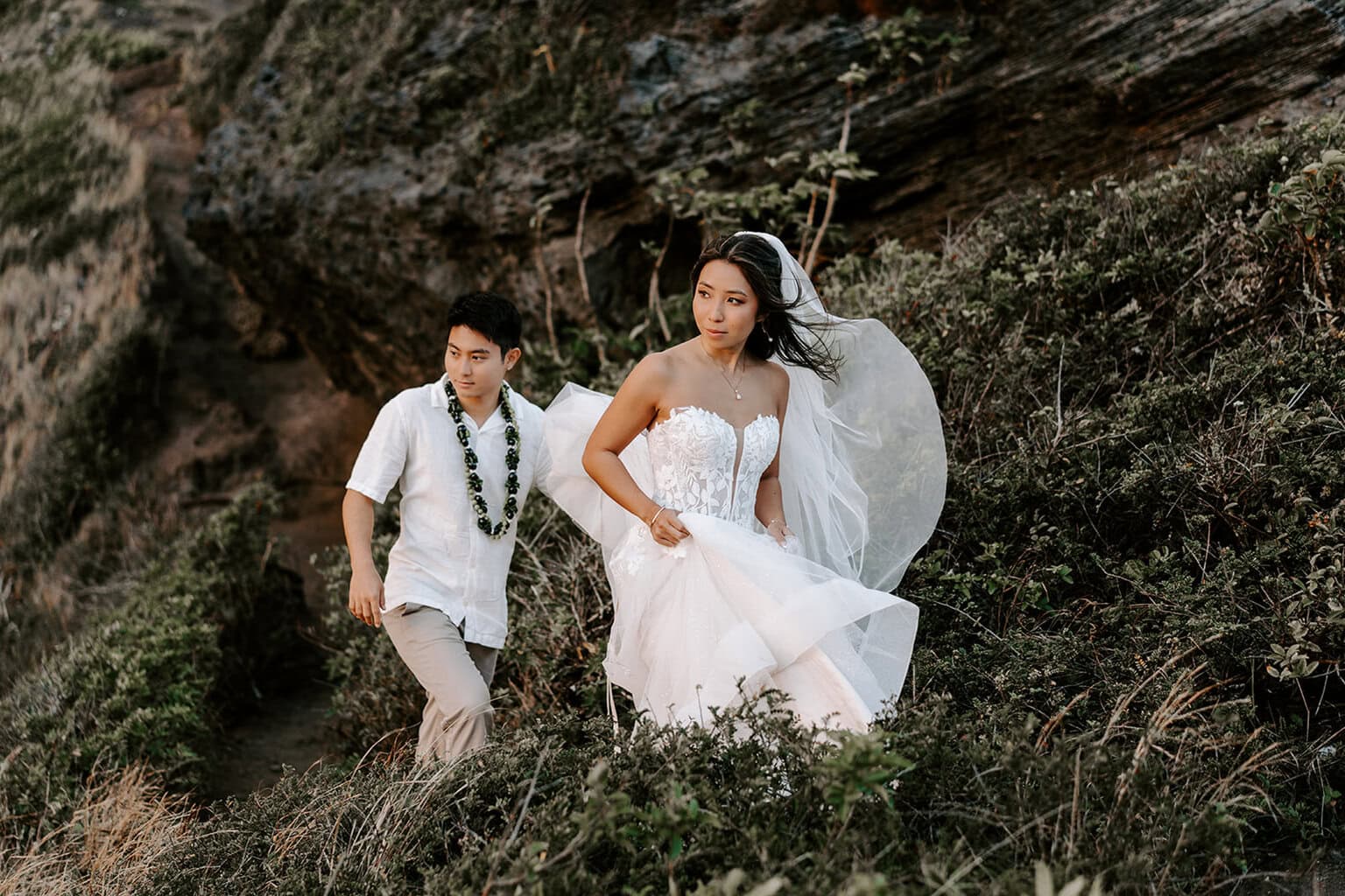 newlyweds hiking up a mountain trail during their Oahu elopement.