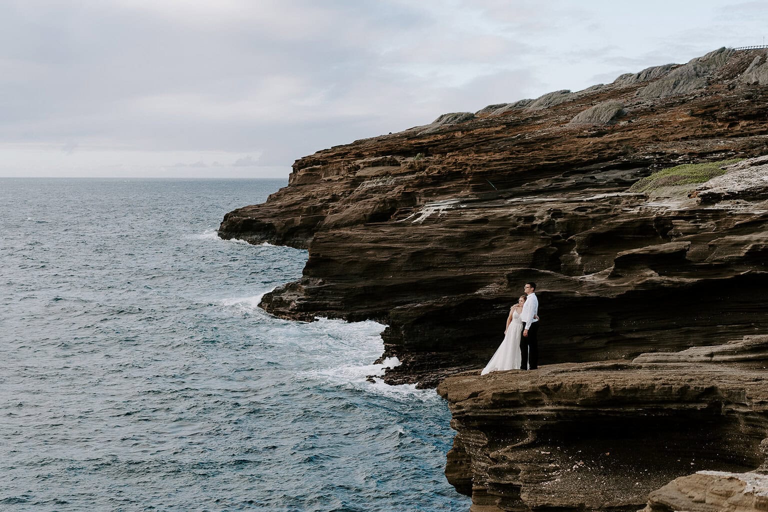 Newlyweds taking in the ocean from a cliffside view during their oahu elopement.