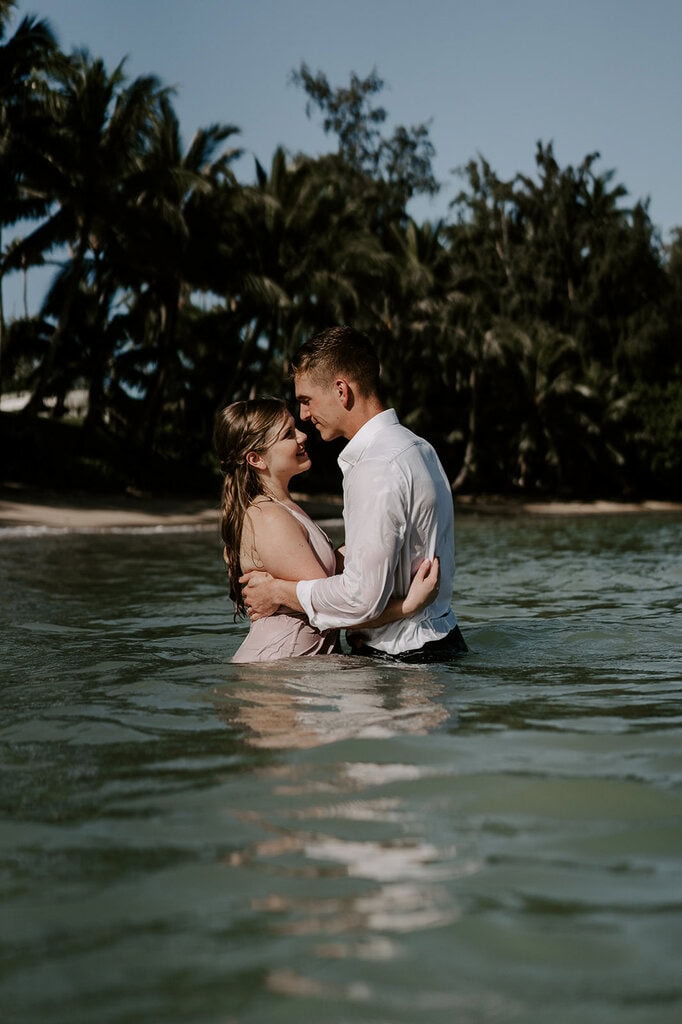 newlyweds hugging in the ocean water.