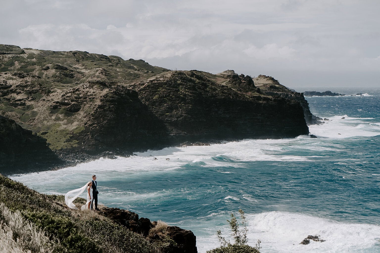 newlyweds standing in a cliffside overlooking the ocean during their Maui elopement.