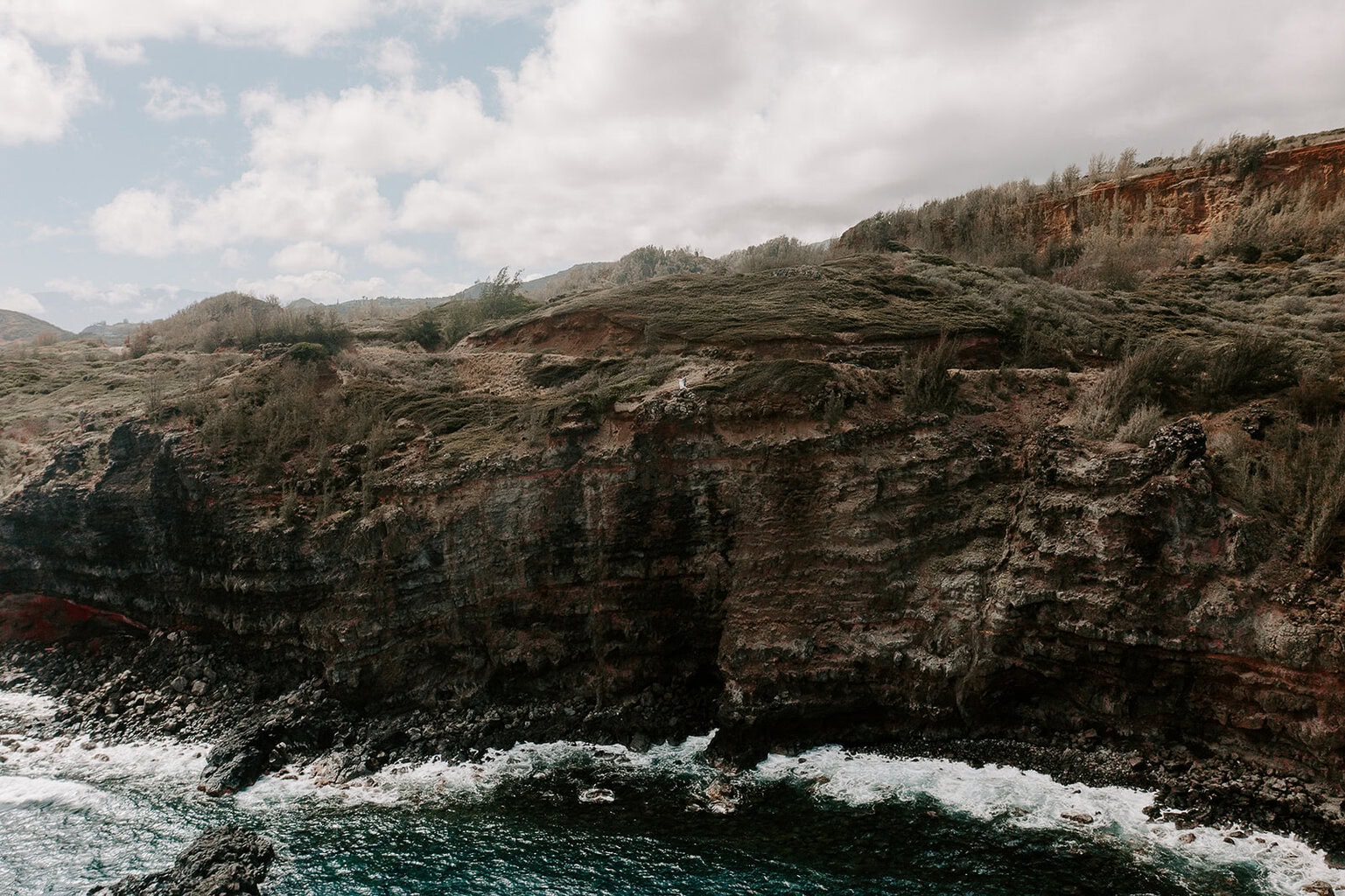 newlyweds standing on a cliffside above the water during their Maui elopement.