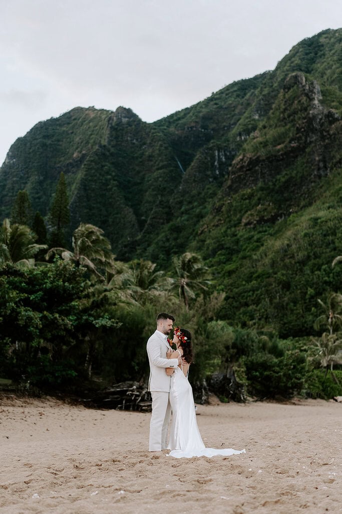 newlyweds hugging on the sand during their kauai elopement.