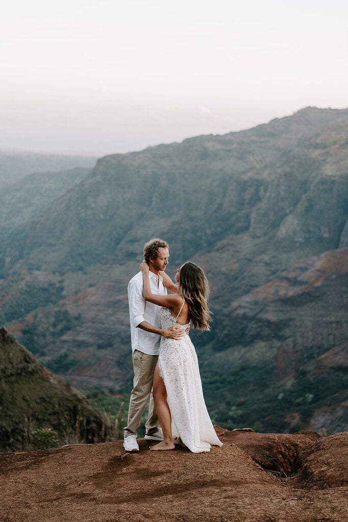 newlyweds hugging at the edge of Waimea canyon.