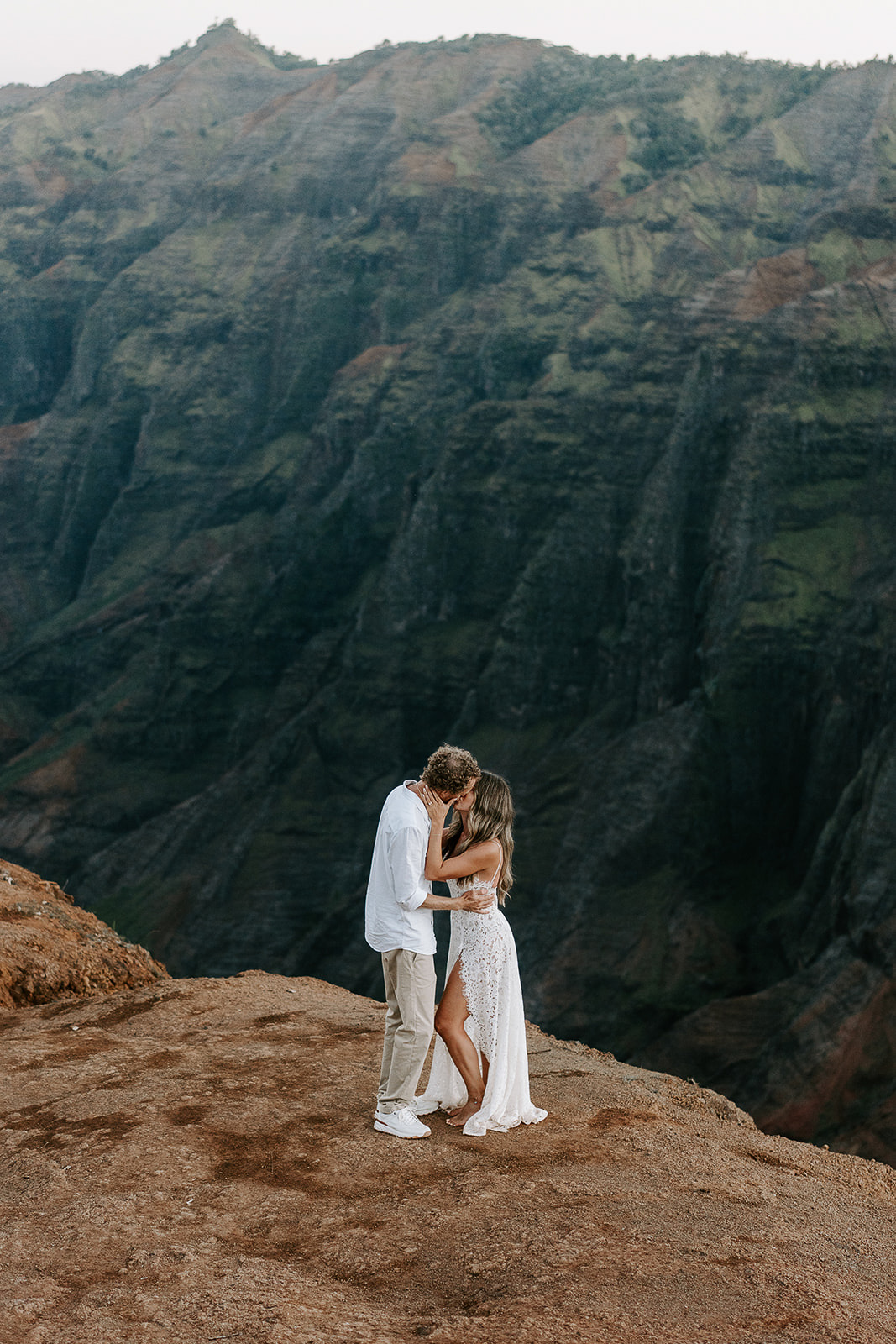 newlyweds kissing at the edge of waimea canyon during their kauai elopement.