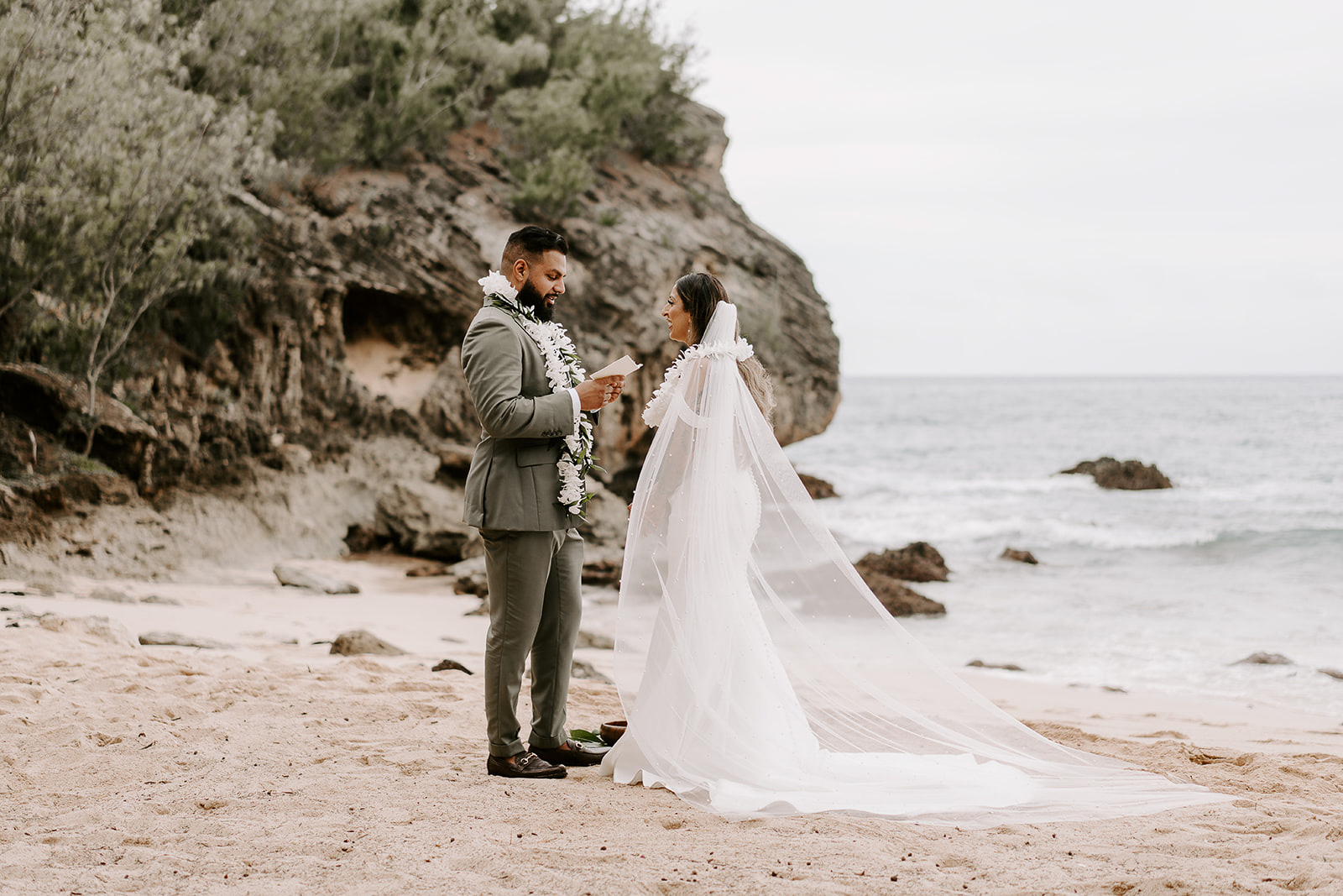 newlyweds exchanging vows on a sandy beach during their kauai elopement.