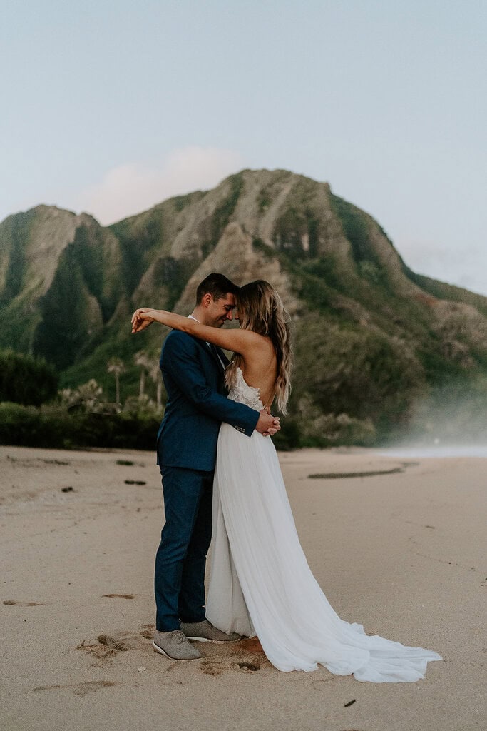 newlyweds hugging on a golden sand beach during their kauai elopement.