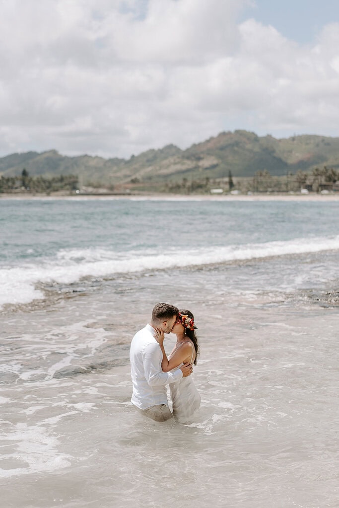 newlyweds kissing in the ocean during their trash the dress hawaii session.