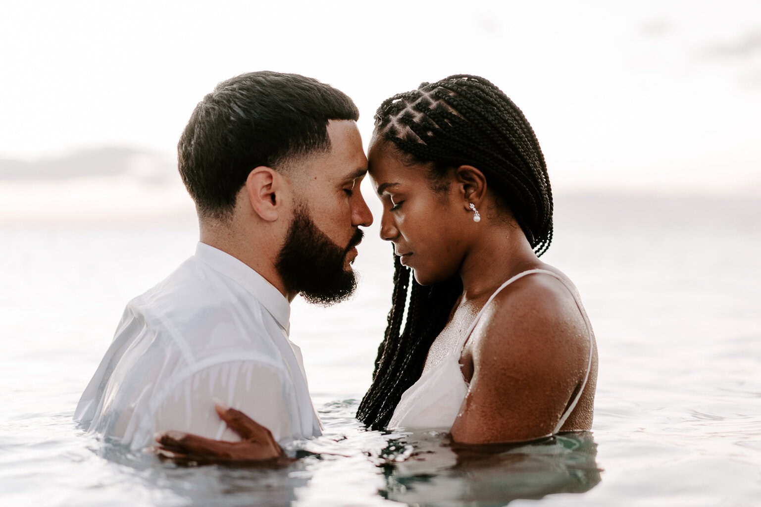 newlyweds hugging wading in the ocean.
