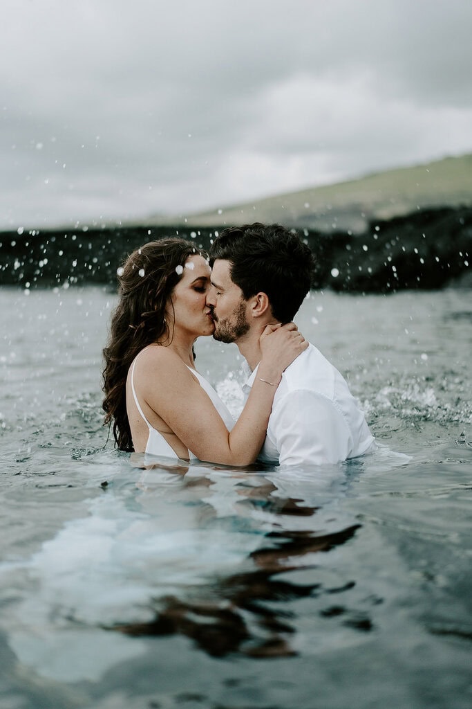 Newlyweds kissing in a tide pool.