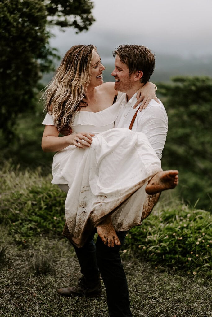 The groom carrying his bride wearing a dirty dress during their trash the dress Hawaii session.