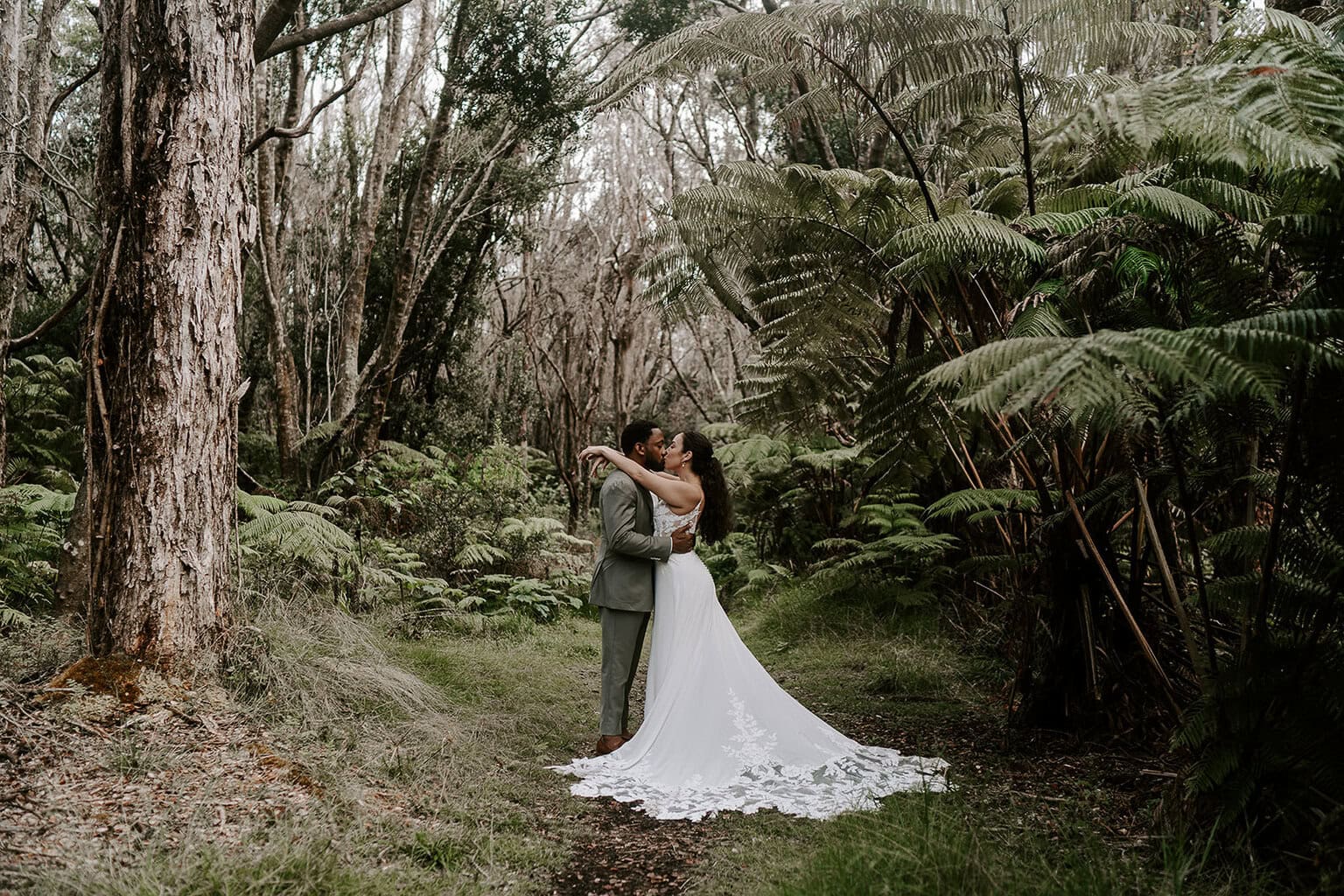 newlyweds kissing in a jungle during their Volcanoes National Park wedding.