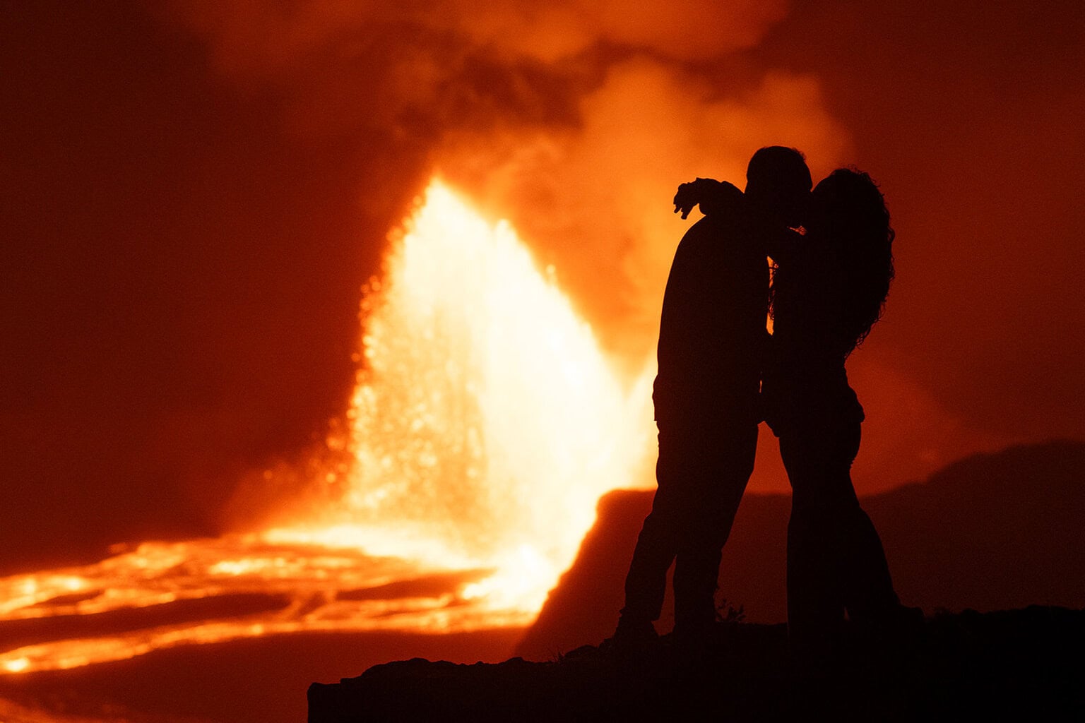 a couple kissing with a volcanic eruption happening in the background.