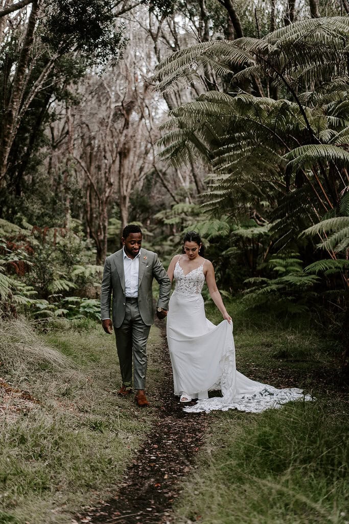 newlyweds walking down a jungle path during their Volcanoes National Park wedding.