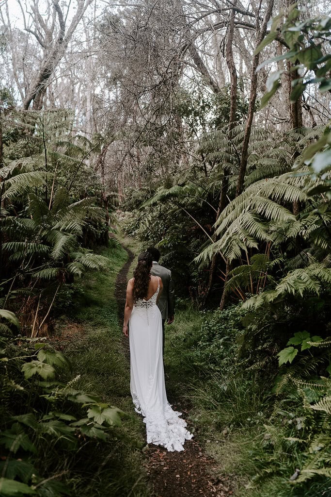 newlyweds walking down a jungle path during their Volcanoes National Park wedding.