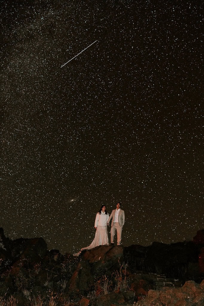 newlyweds holding hands under the milky way.
