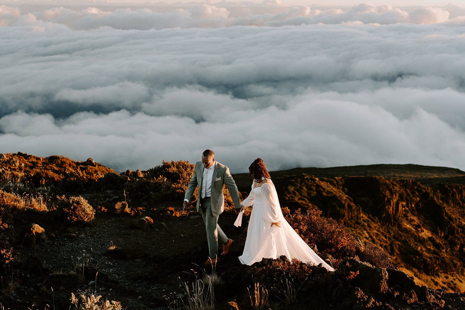 newlyweds walking on top of a mountain summit.