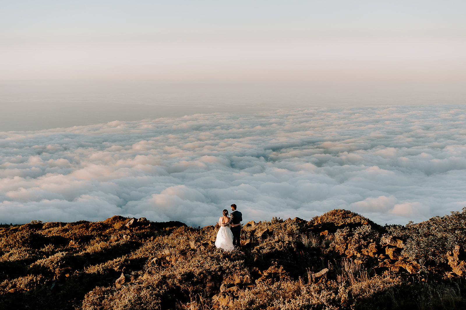 newlyweds hugging above the clouds during their Haleakalā wedding.