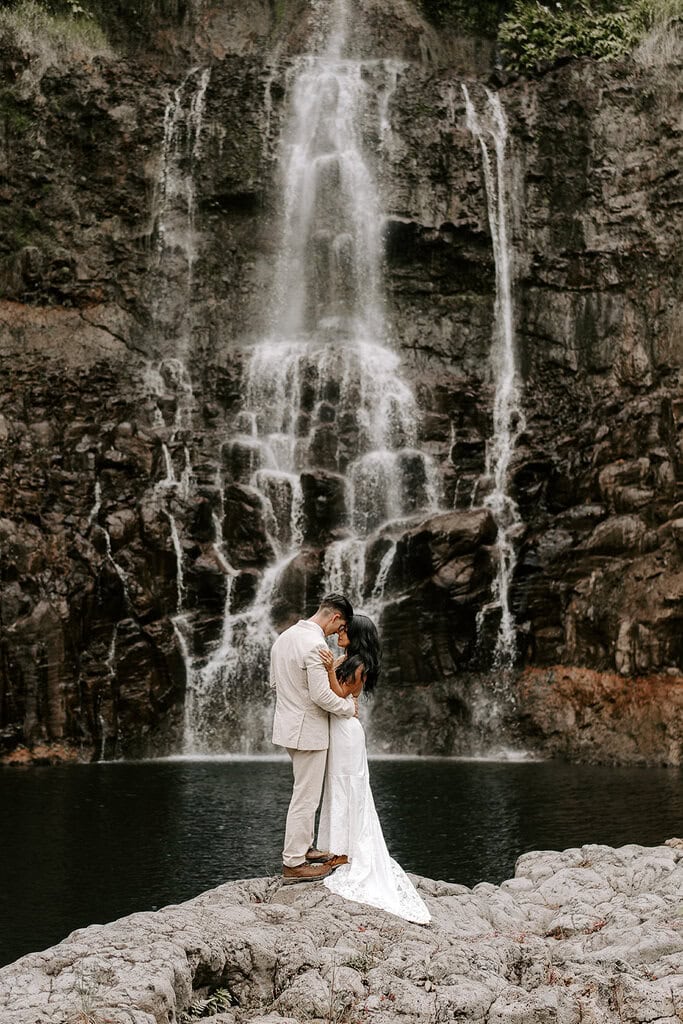 newlyweds kissing in front of a cascading waterfall.