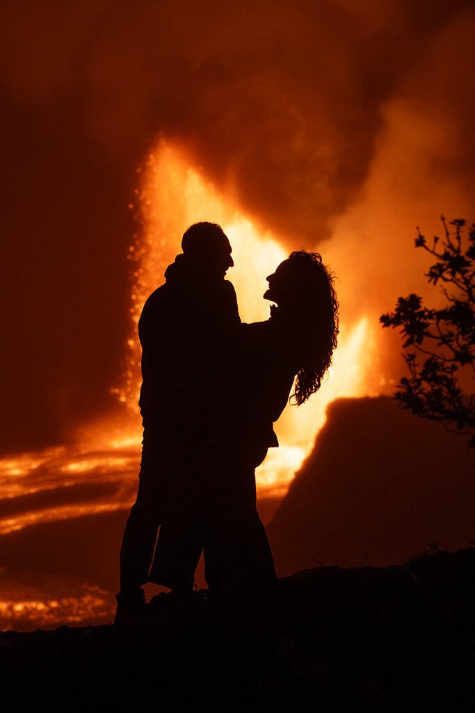 couple hugging in front of an active volcano at Volcanoes National Park, one of the best places to get married on the Big Island.