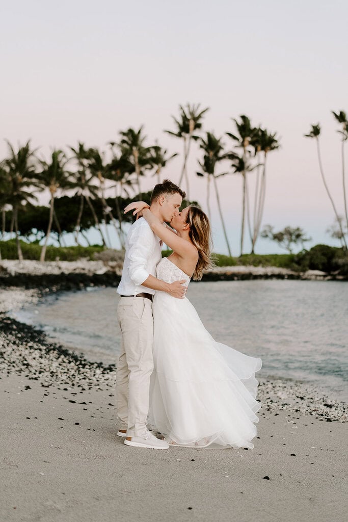 newlyweds kissing on a golden sand beach, one of the best places to get married on the Big Island.