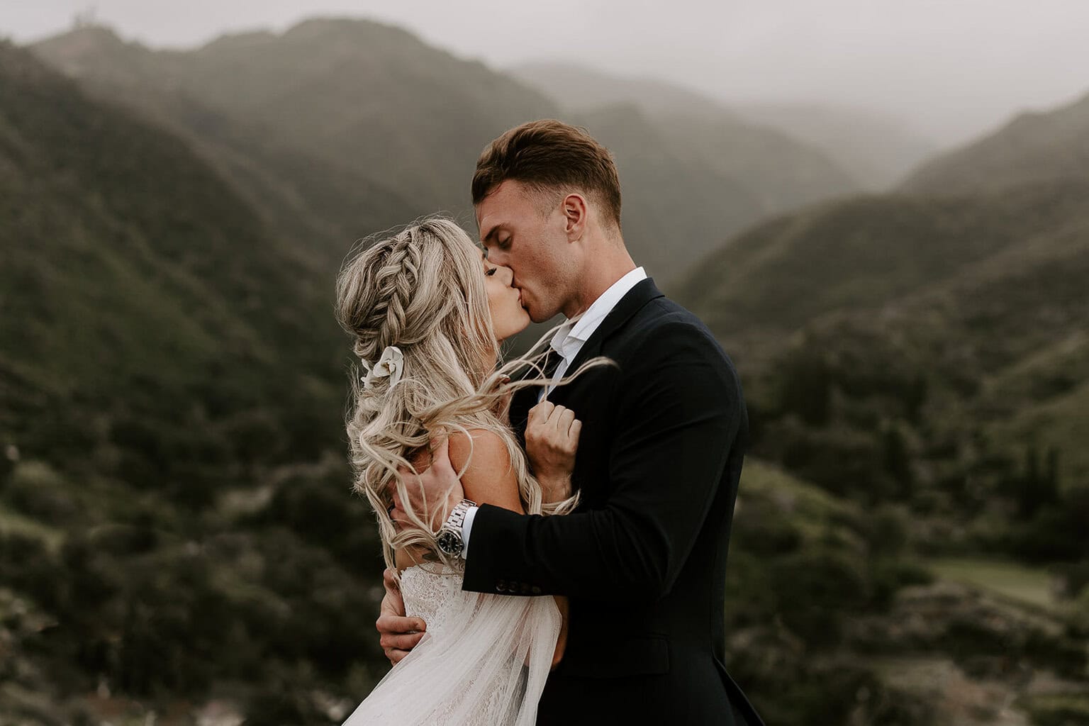 Newlyweds kissing in front of a green valley, one of the best Maui elopement locations.