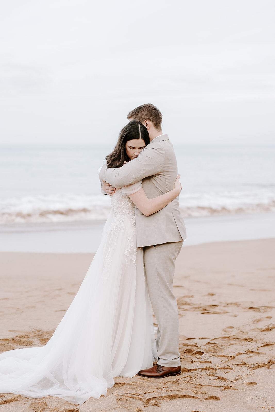 newlyweds hugging on a sandy beach in Hawaii, one of the best Maui elopement locations.