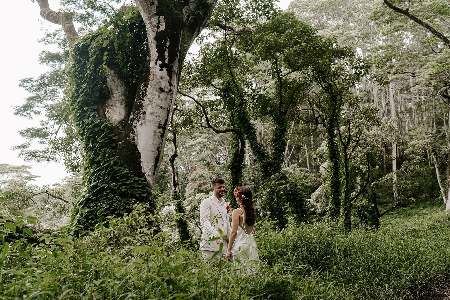 Newlyweds holding hands in the middle of a jungle, one of the best Kauai elopement locations.