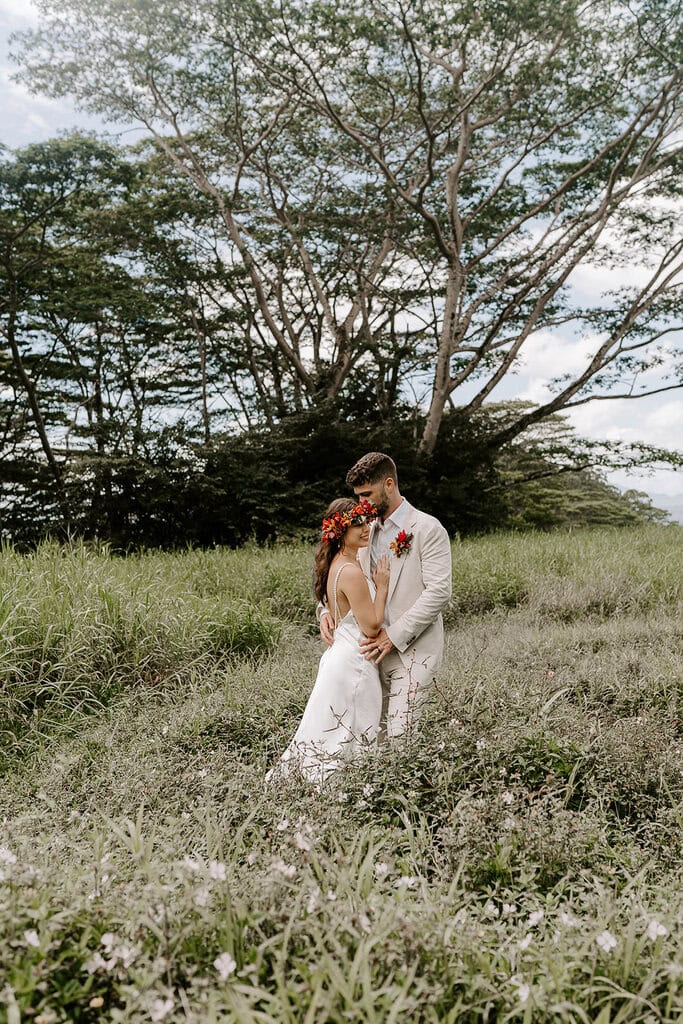 Newlyweds hugging in a field in Kauai.