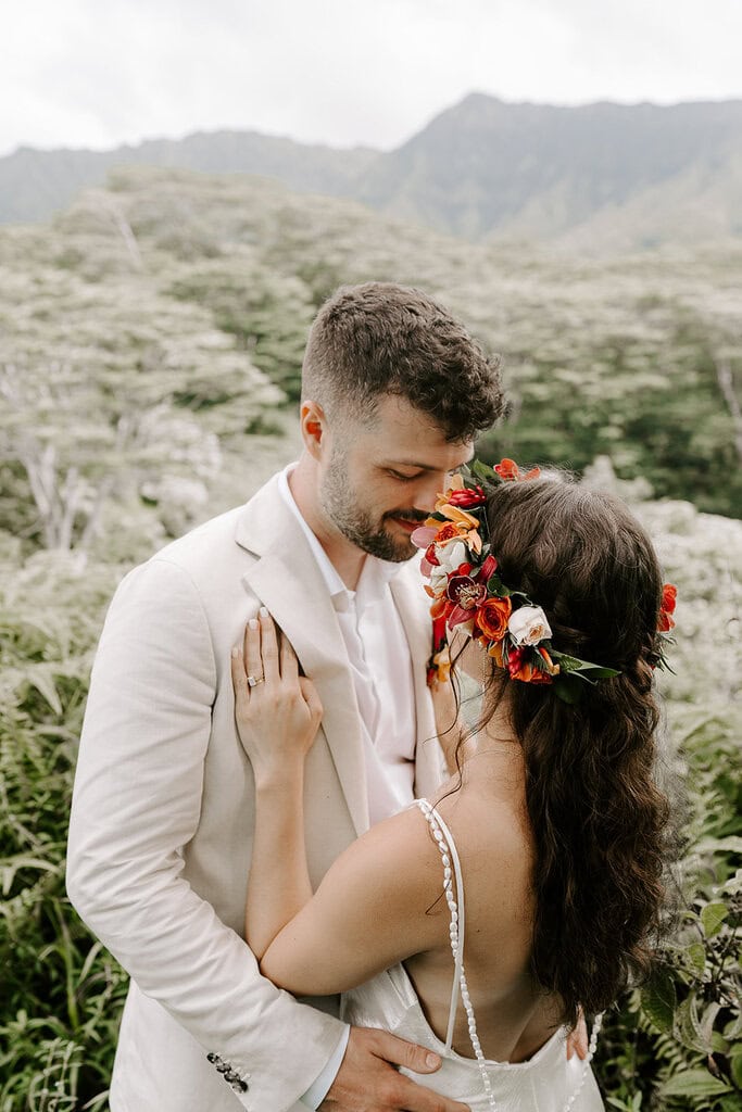 Newlyweds hugging on a green mountain, one of the best Kauai elopement locations.