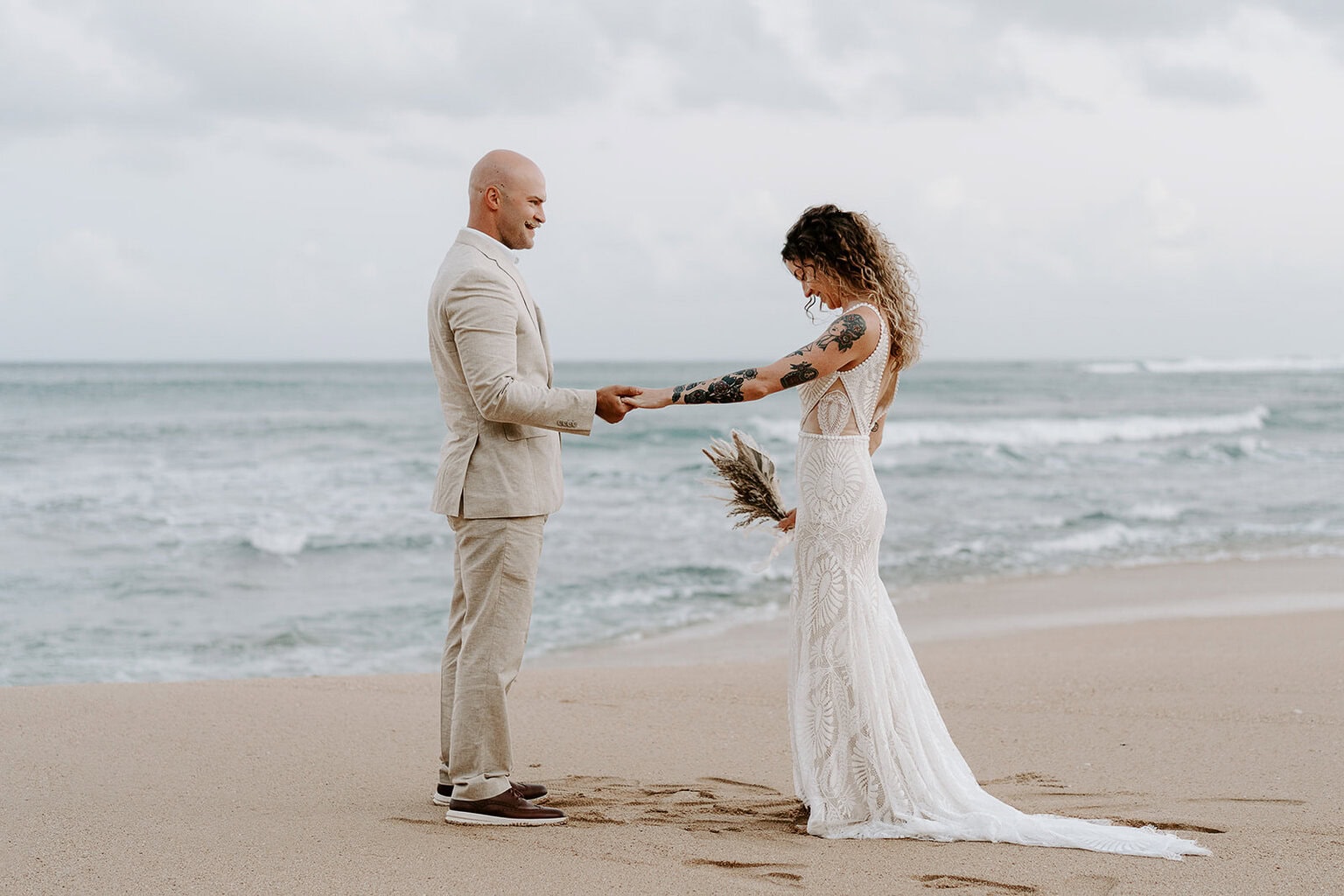 Newlyweds holding hands on a beach in Kauai.