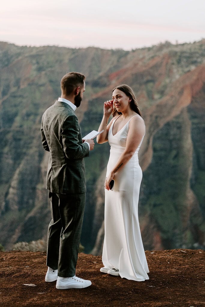 Newlyweds exchanging vows at sunrise as they elope in Waimea Canyon.