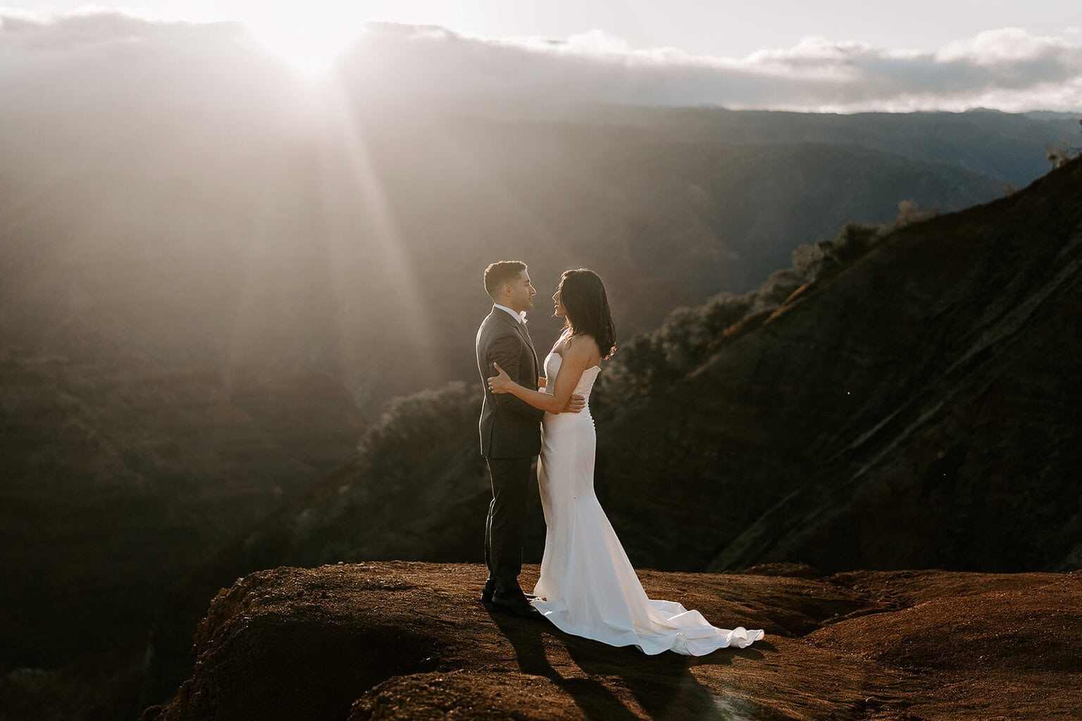 Newlyweds holding each other at sunrise as they elope in Waimea Canyon