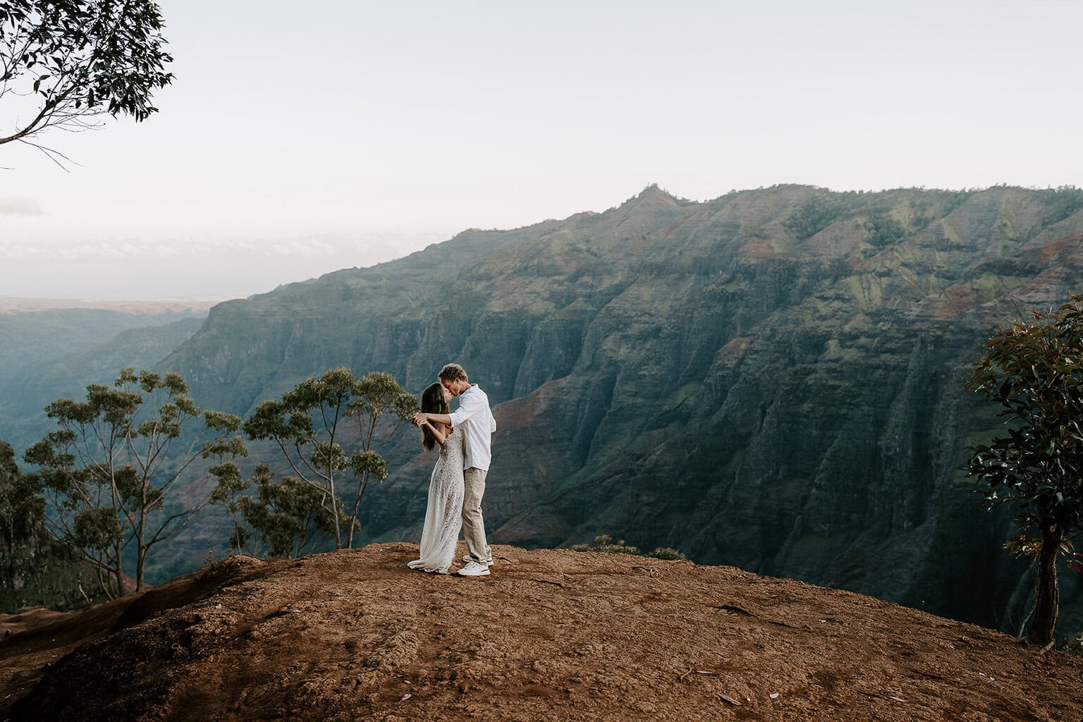 Newlyweds dancing during golden hour with an expansive canyon behind them.
