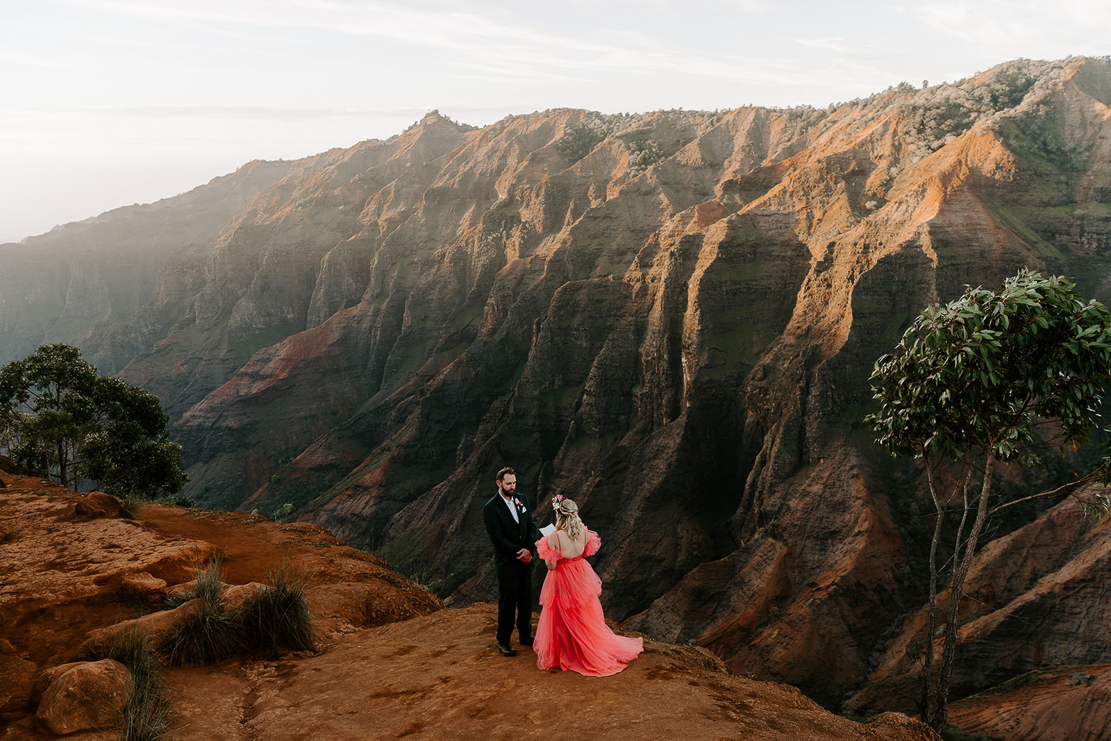 Newlyweds exchanging vows standing at the rim of waimea canyon during their elopement.